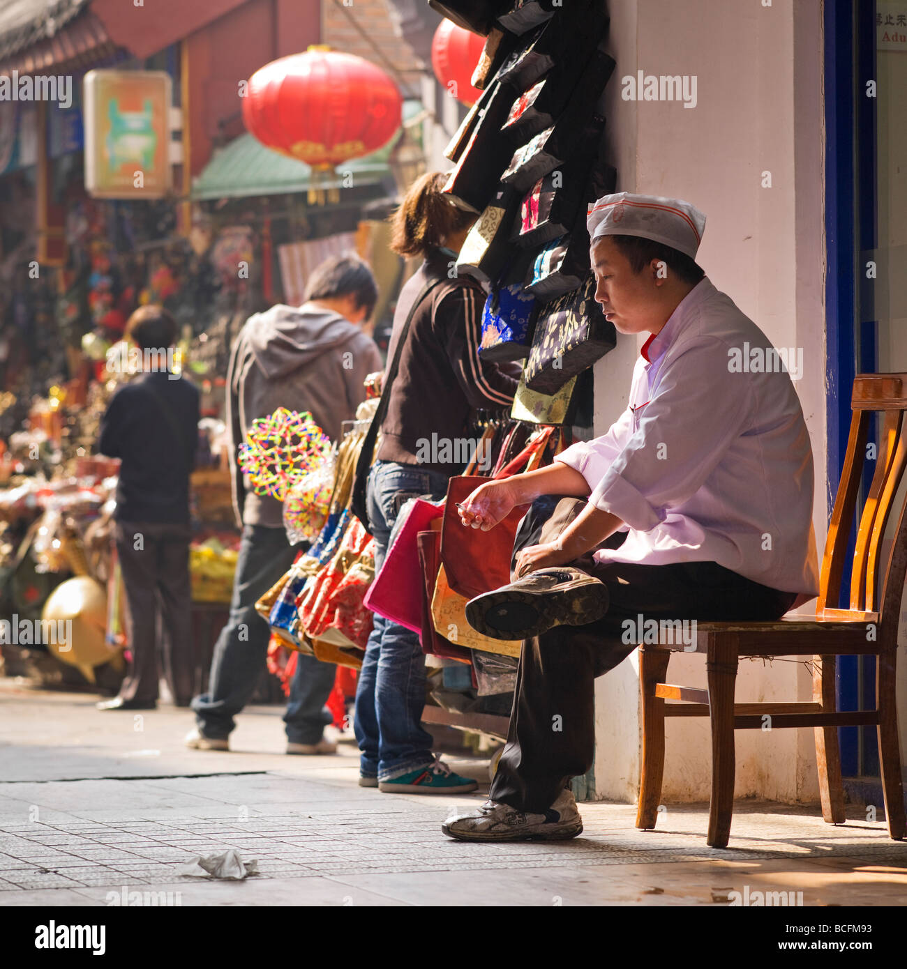 A food stall holder takes a cigarette break in a popular tourist market off Wangfujing Street Beijing China Stock Photo