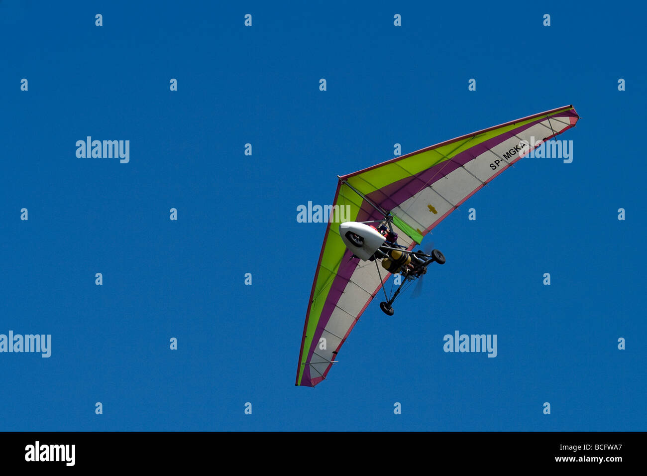 Photograph of Ultralight trike flying above on intense blue sky. Stock Photo