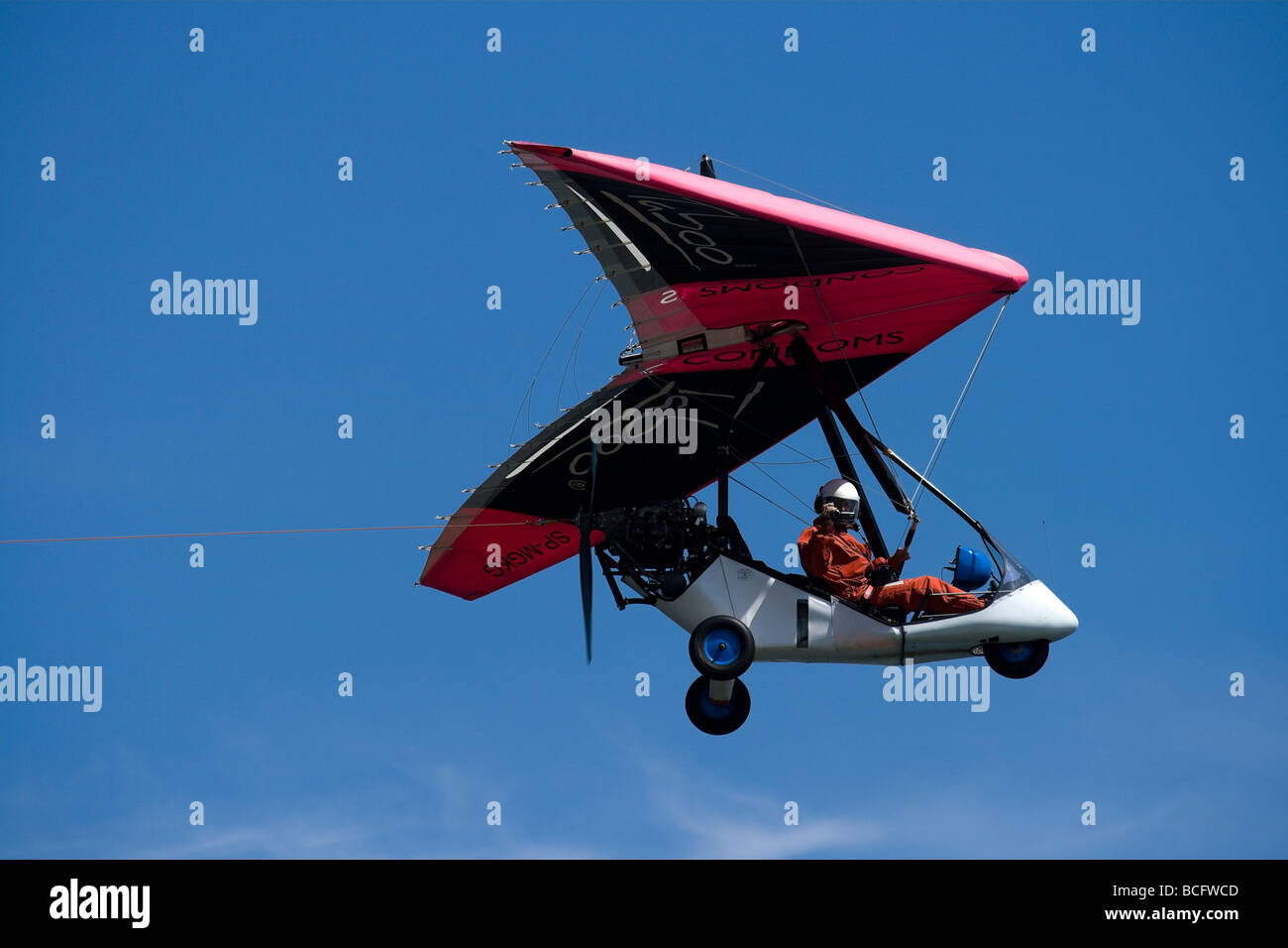 Photograph of Ultralight trike with condom ads on its wing,  flying on intense blue sky. Stock Photo