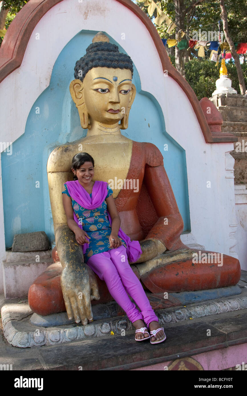 Kathmandu, Nepal.  Young Nepali Woman Reclines in the Lap of a Buddha Lining the Stairs  to the Swayambhunath Temple. Stock Photo