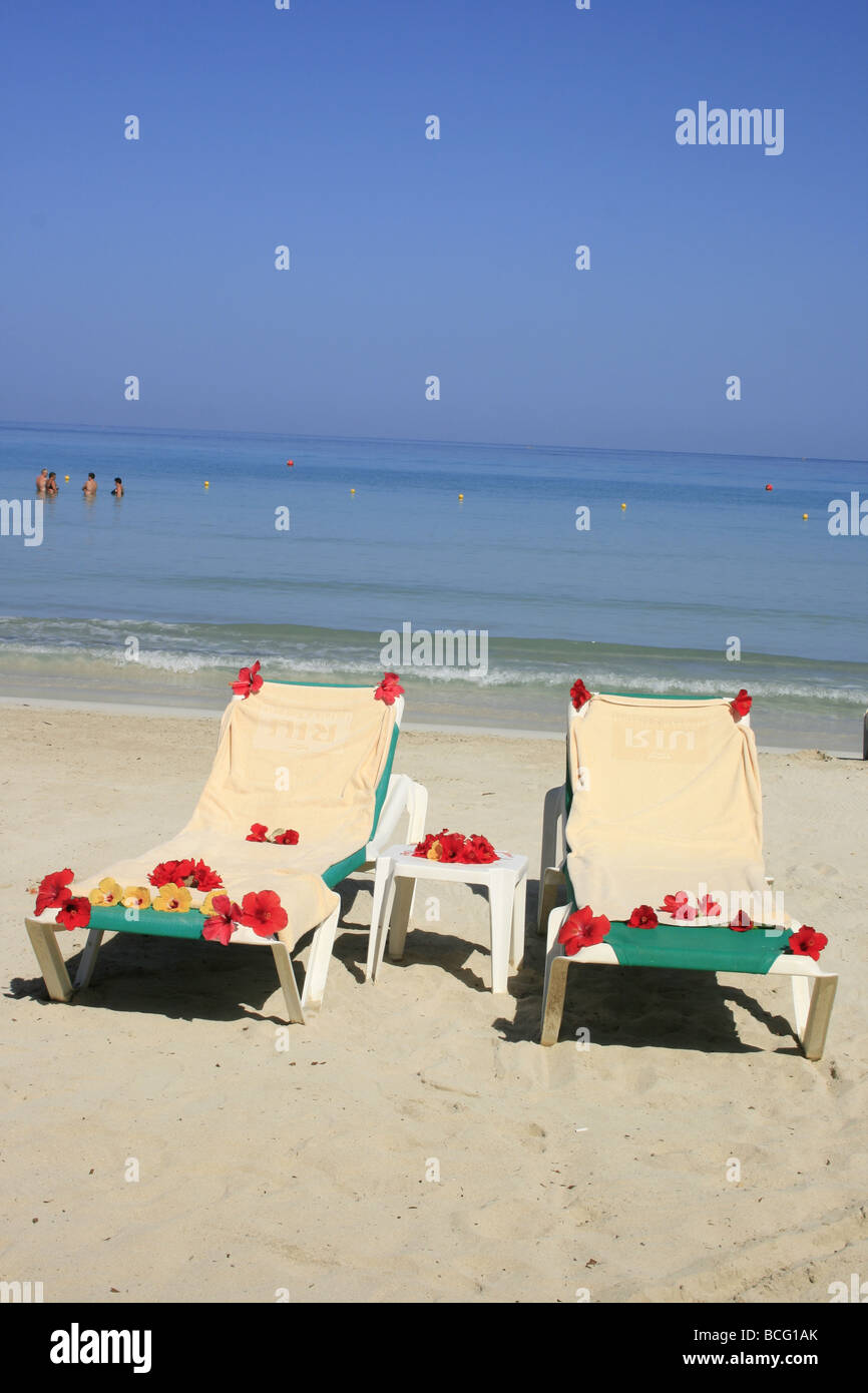 Loungers with tropical flowers, Bloody Bay beach, Negril, Jamaica Stock Photo