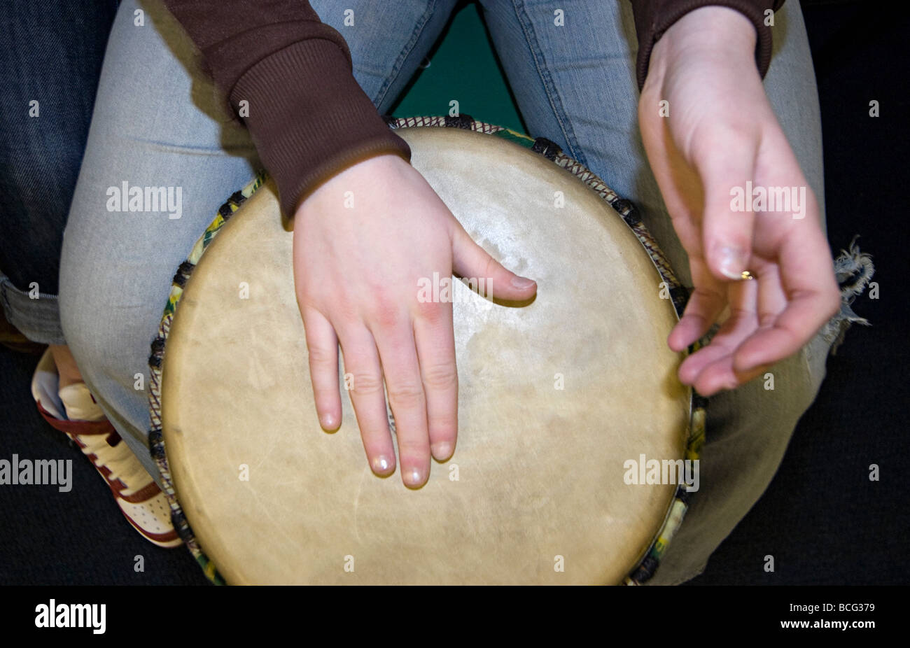 a while girls hand hitting an african drum in a music Stock