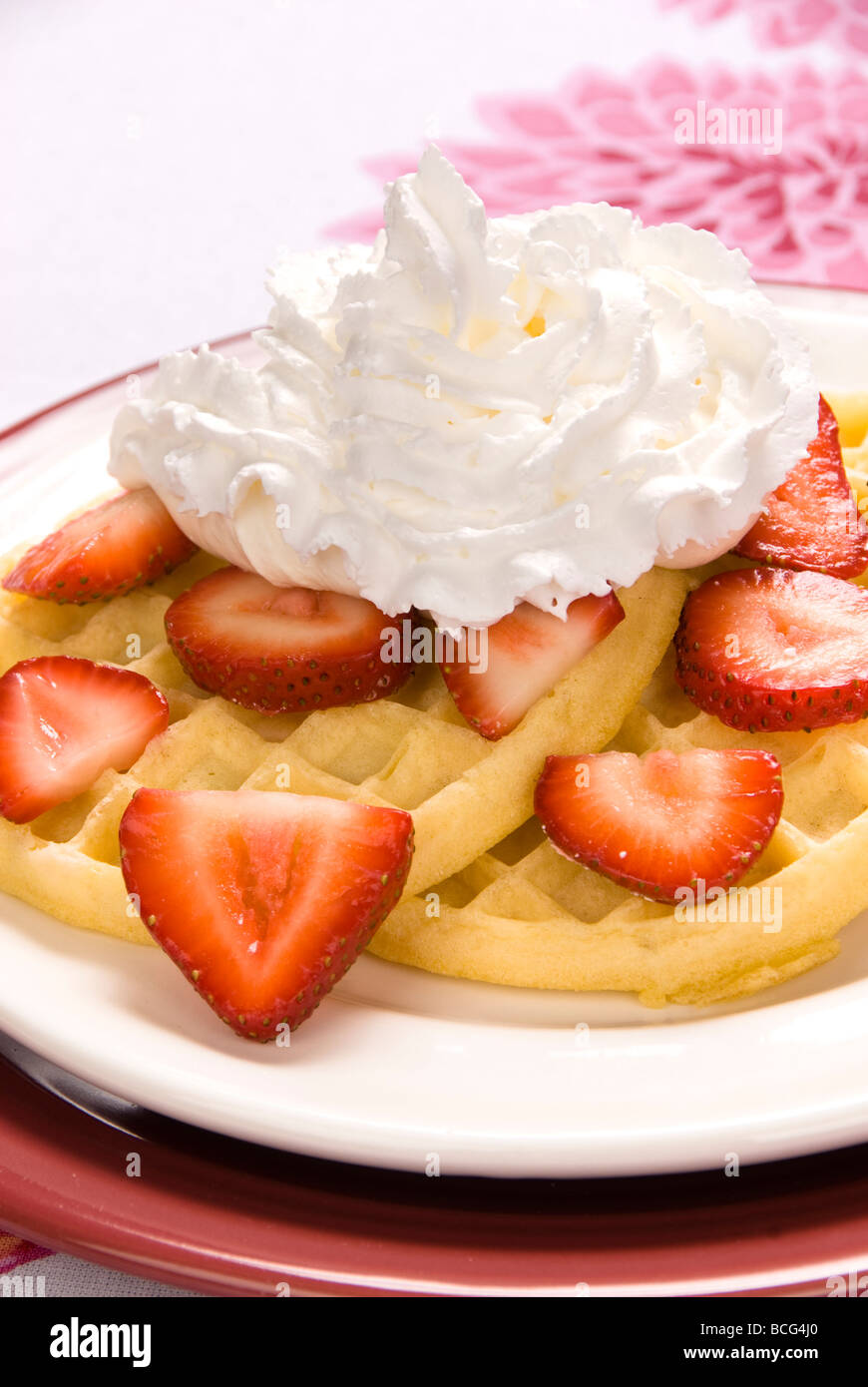 A plate of strawberry waffles with sweet whipped cream Stock Photo