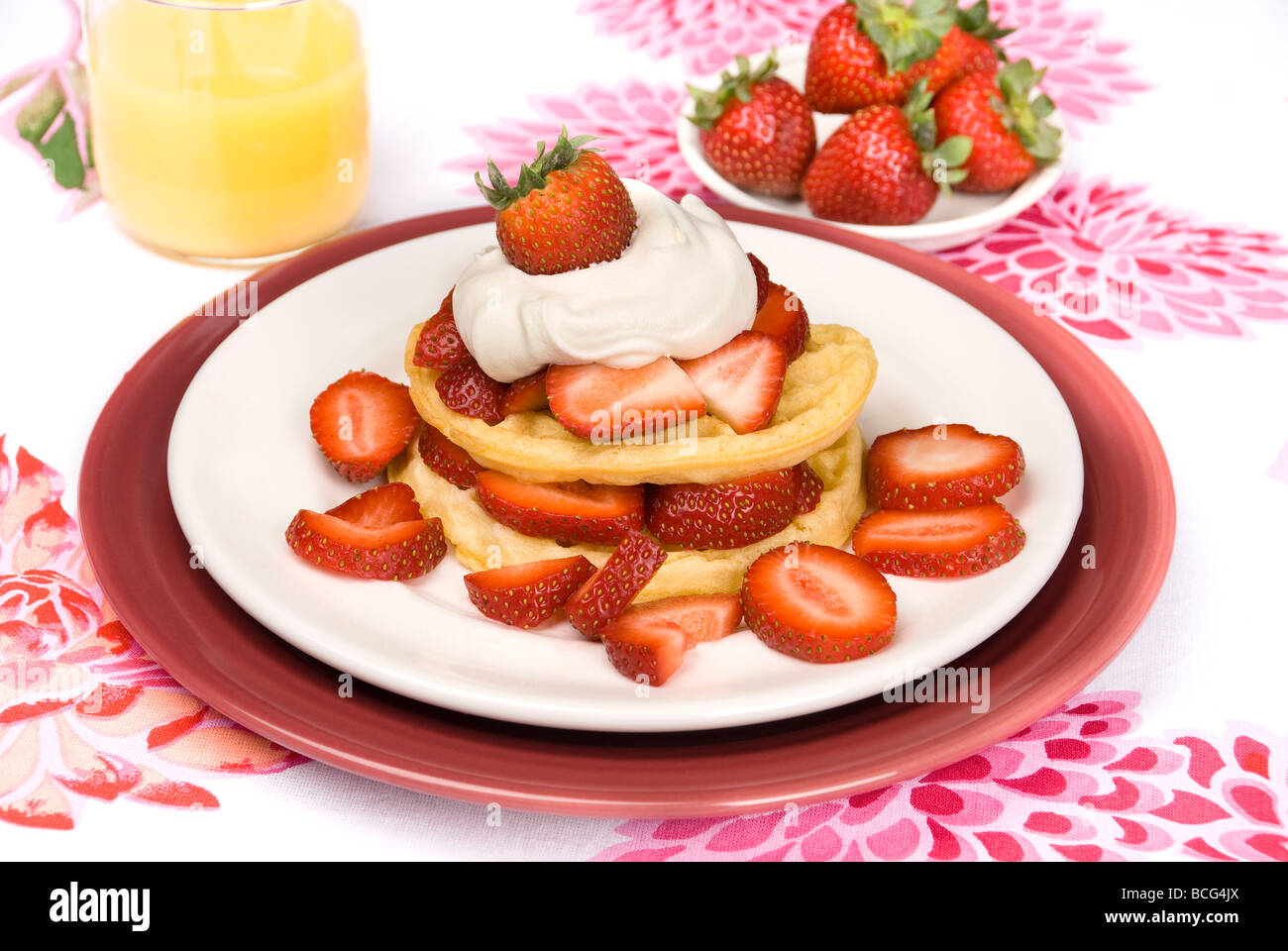 A delicious breakfast meal of strawberry waffles with whipped cream and orange juice Stock Photo