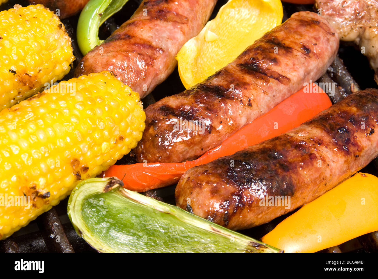 Grilled bratwurst and corn on the cob smothered in bell peppers ready to eat during a picnic Stock Photo