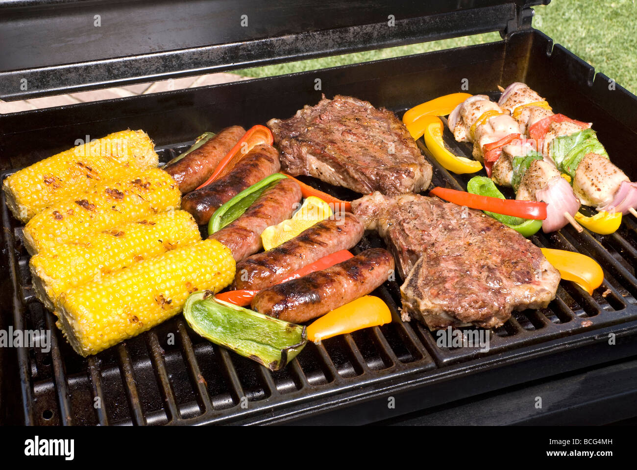 A barbecue spread of corn on the cob bratwurst steak sirloin fillets and chicken kebabs Stock Photo
