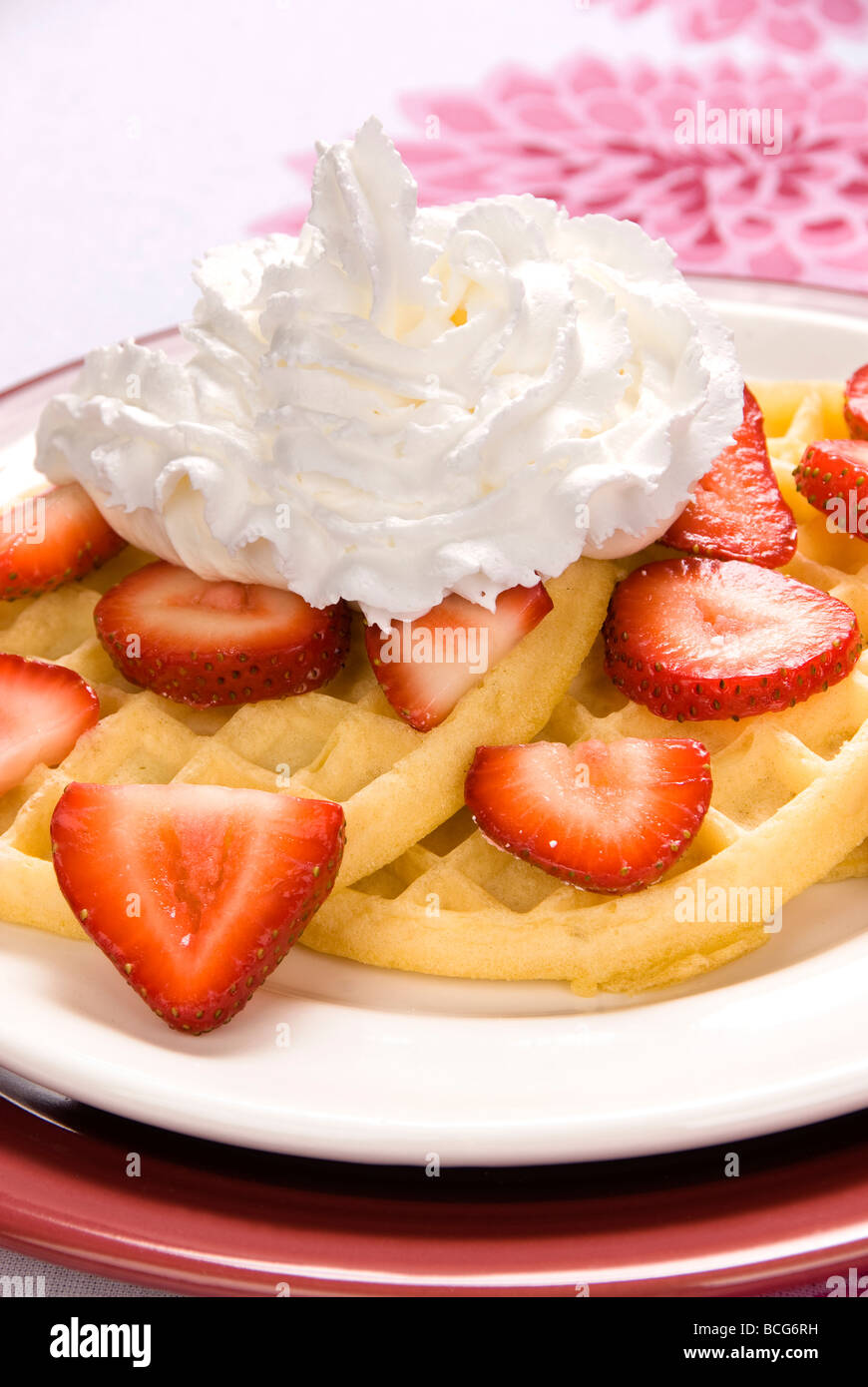 A plate of strawberry waffles with sweet whipped cream Stock Photo