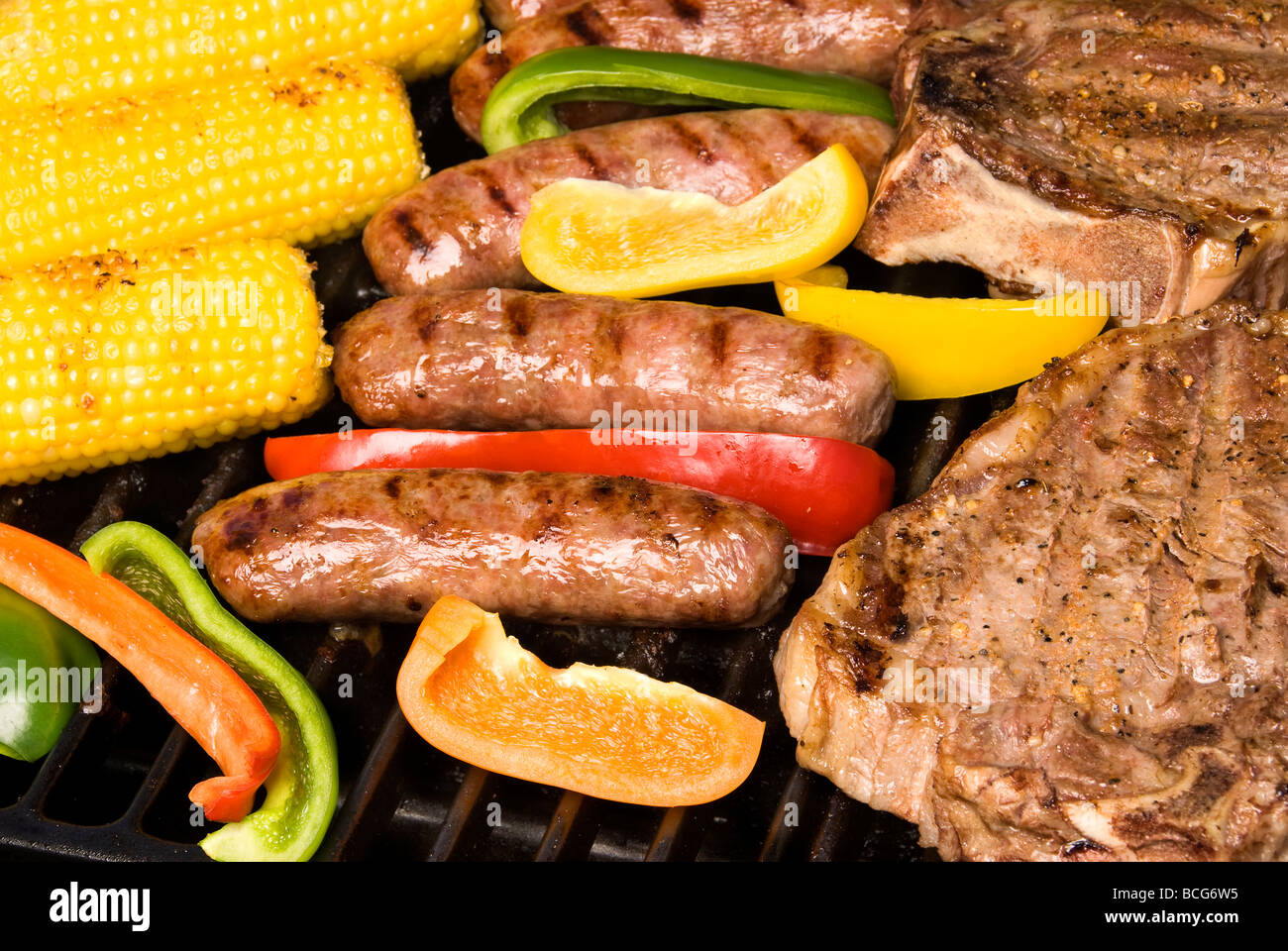 A barbecue spread of bratwurst corn on the cob and sirloin steak with bell pepper garnish for awesome flavor Stock Photo