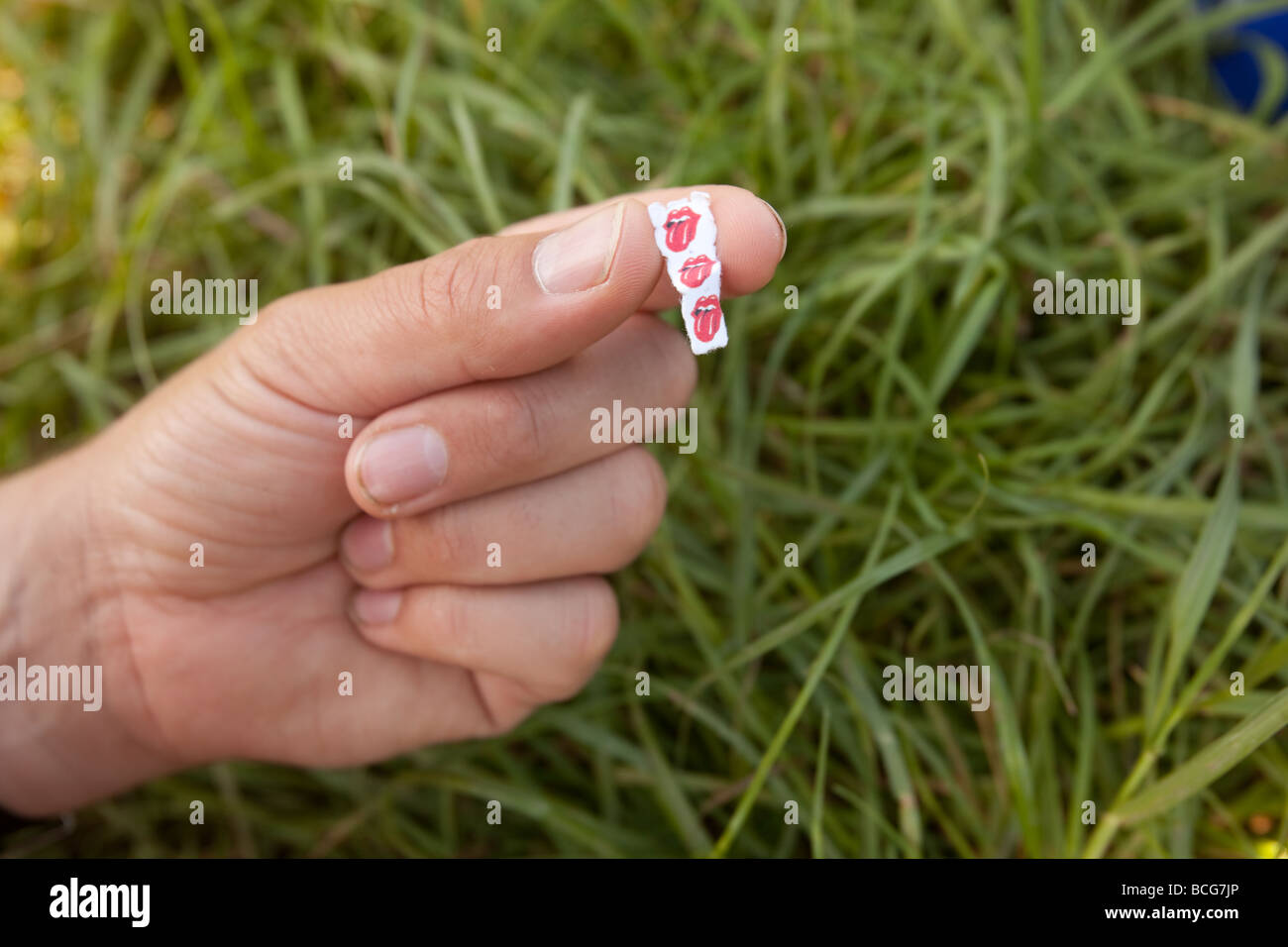Acid LSD trips or tabs held in a mans fingers Stock Photo