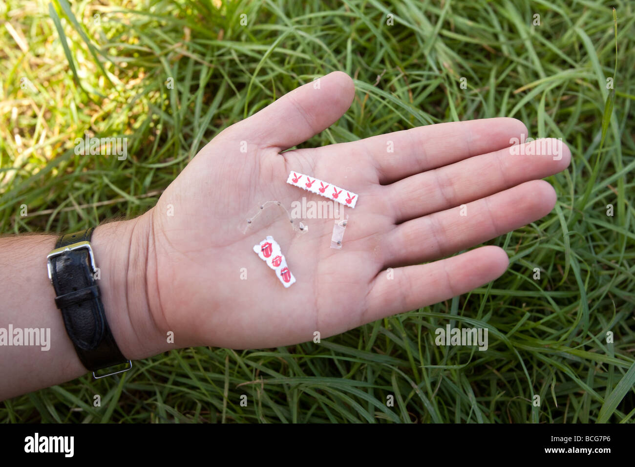Various types of Acid LSD trips and microdots held in a mans hand Stock Photo
