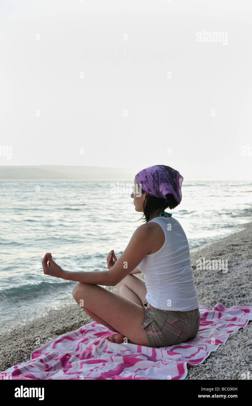 Young woman doing yoga on beach Stock Photo
