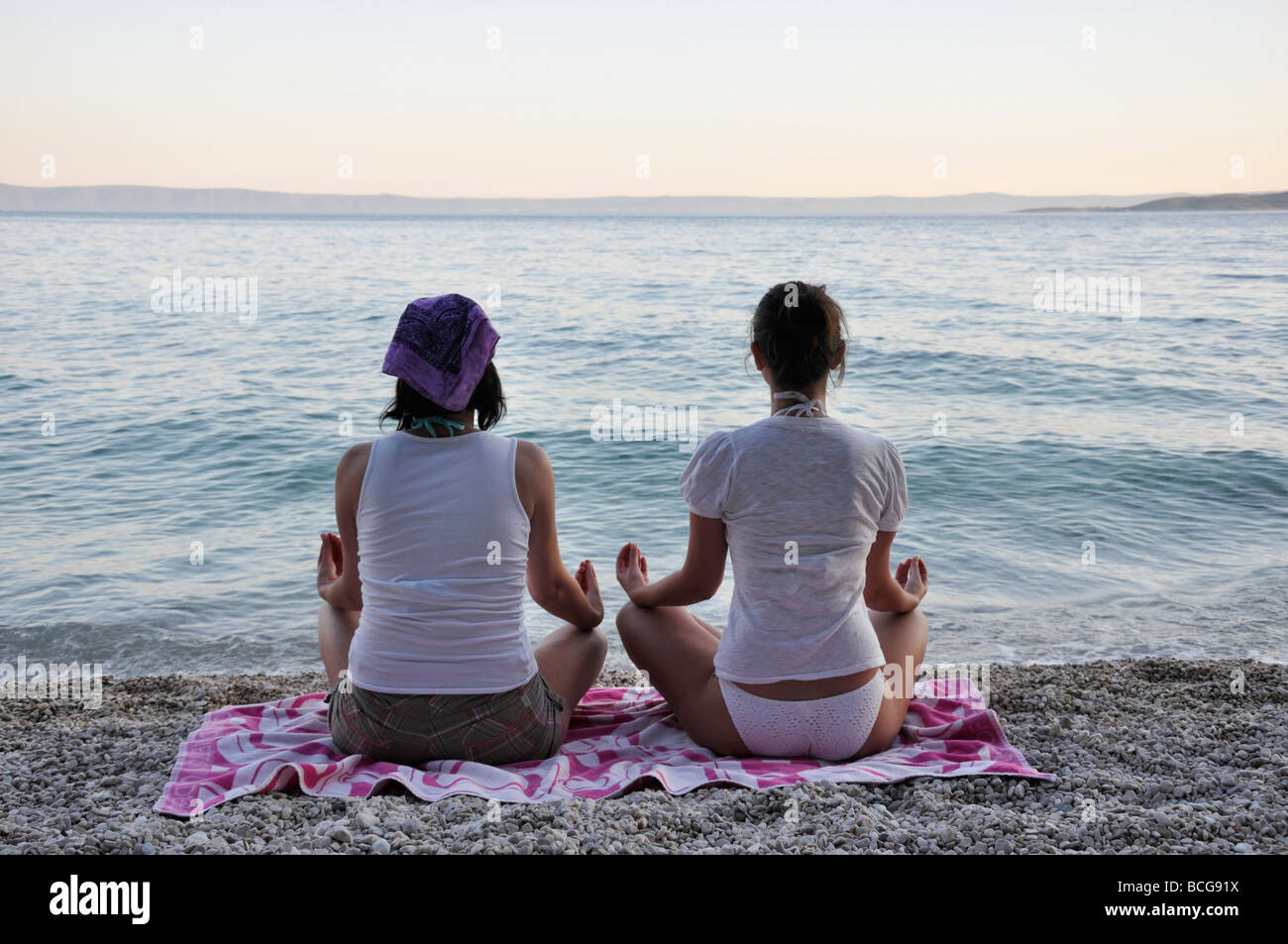 Young women doing yoga on beach Stock Photo