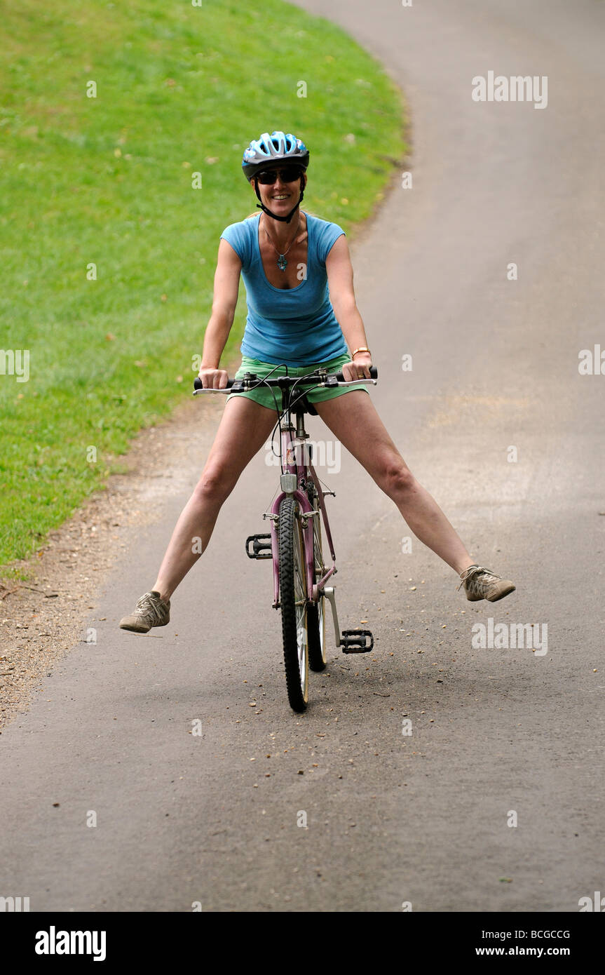 Woman cyclist freewheeling downhill with legs outstretched on a