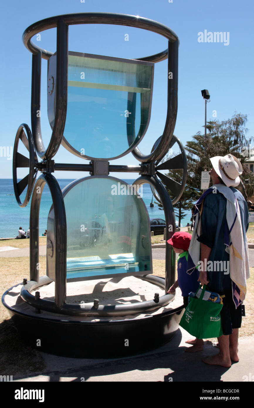 A father and son looking at a giant egg timer sculpture which forms part of the sculpture by the sea exhibition Stock Photo Alamy