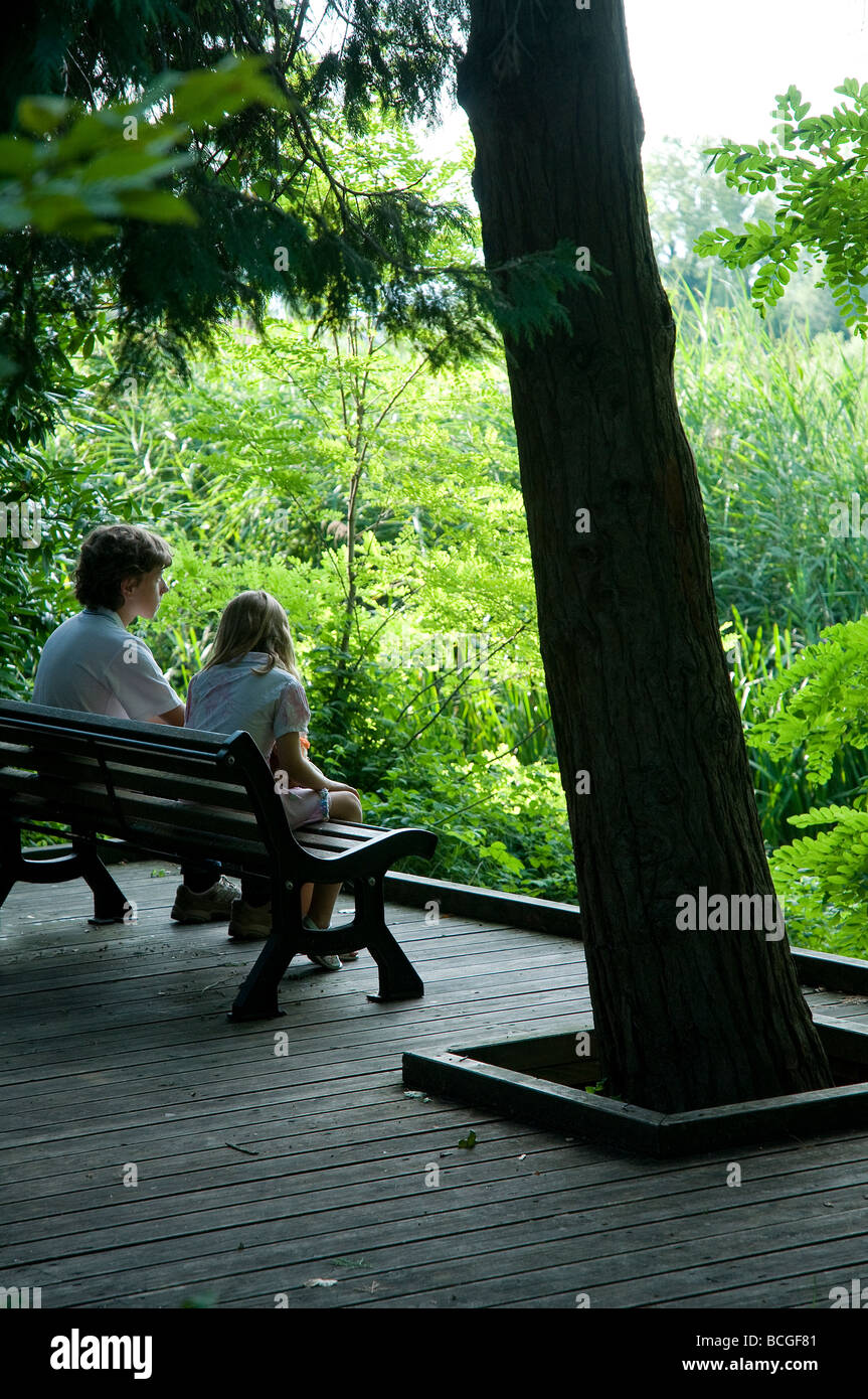 a boy and a girl sitting on a bench at the park Stock Photo - Alamy