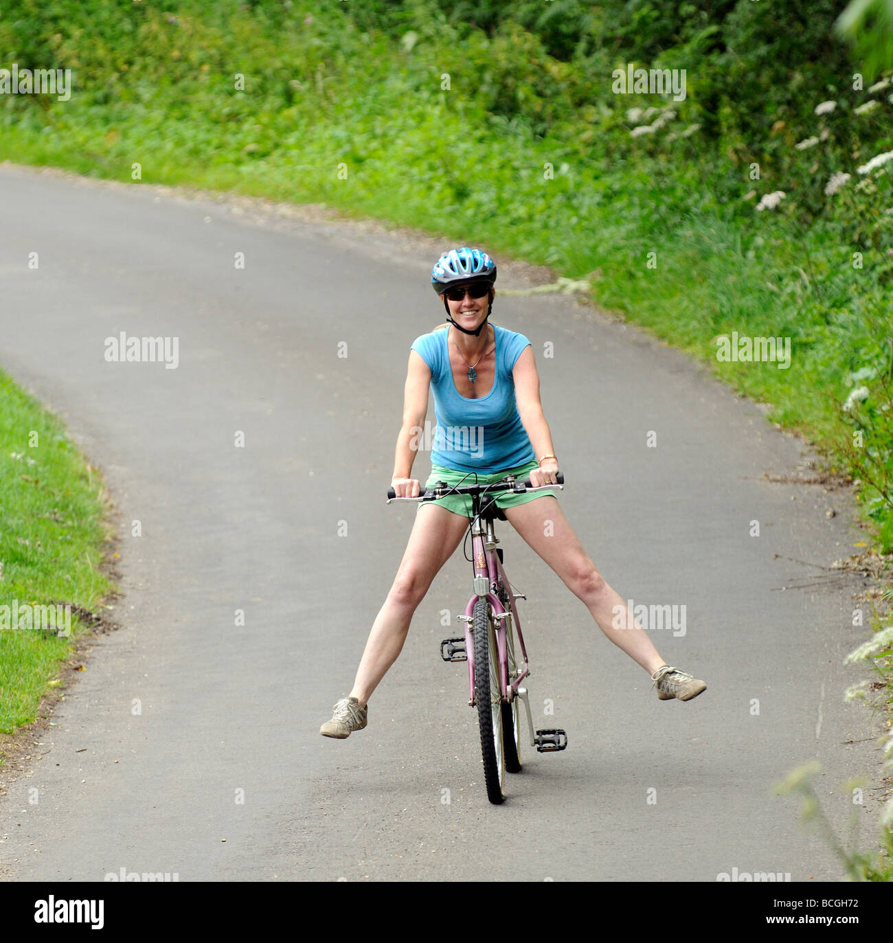 Woman cyclist freewheeling downhill with legs outstretched on a quiet
