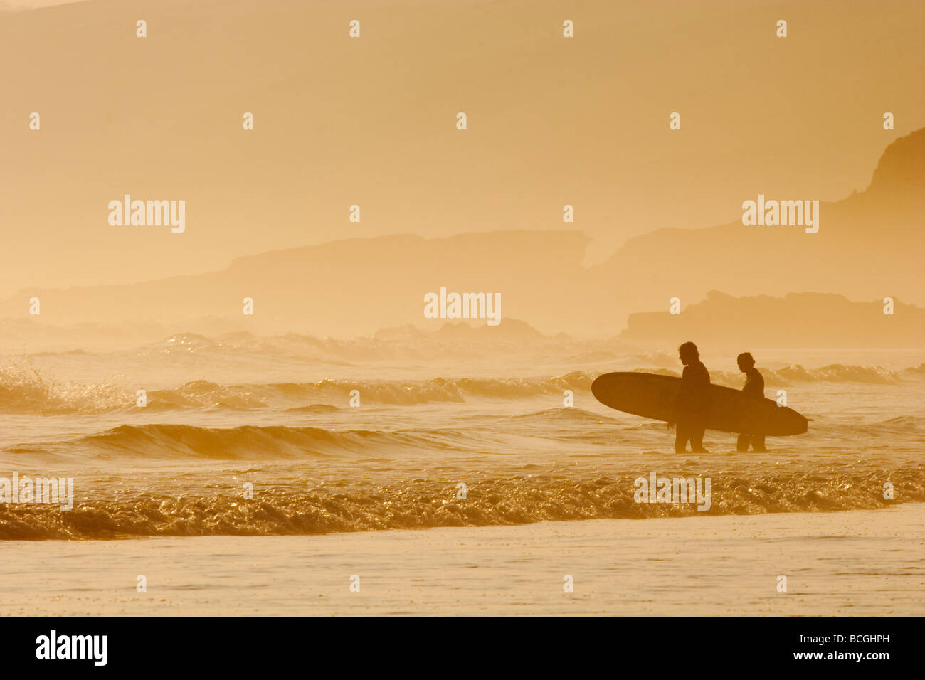 The sun is setting. Mist rolling in from the sea. Surfers off to catch the last wave of the evening. Surfing in Cornwall. Stock Photo