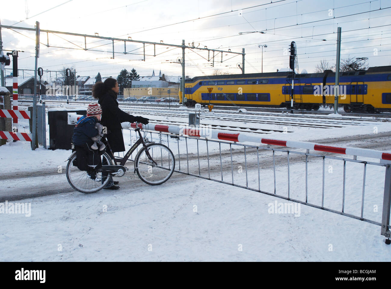 cyclist waiting at railway crossing in winter Stock Photo