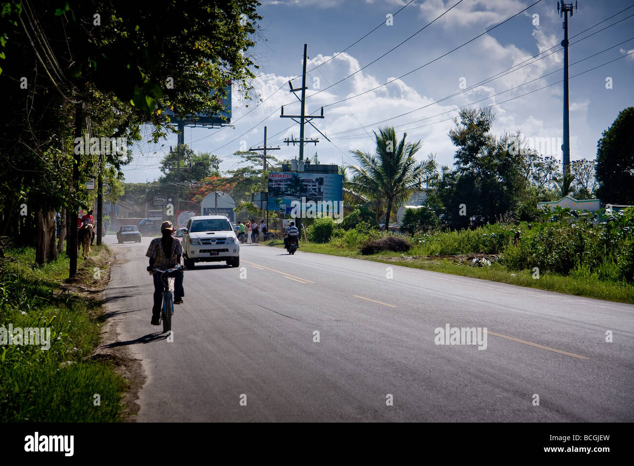 The view from the side of a busy road in Sosua, Dominican Republic showing cars, motorbikes, mopeds, trucks and horses passing b Stock Photo