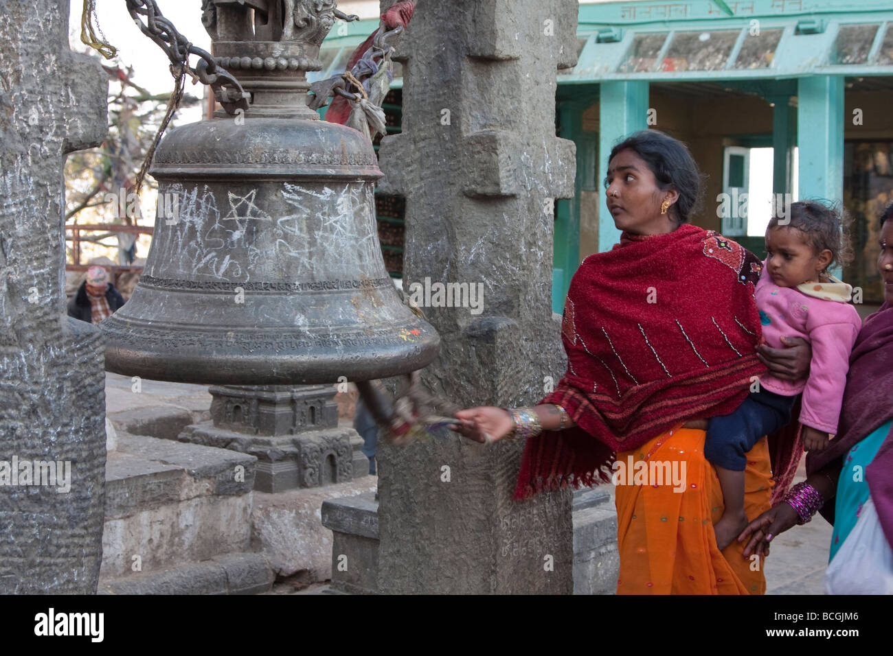 Kathmandu, Nepal. Nepali Worshipper with Child Rings a Bell at Swayambhunath Temple. Bells drive evil spirits away. Stock Photo
