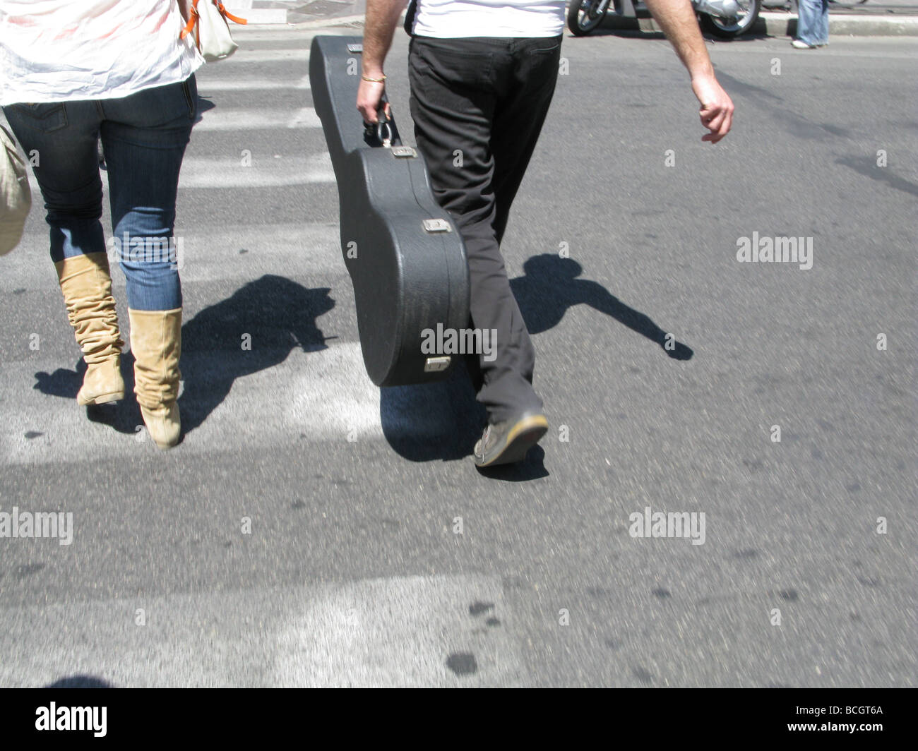 person carrying guitar case in street in town in sun Stock Photo Alamy