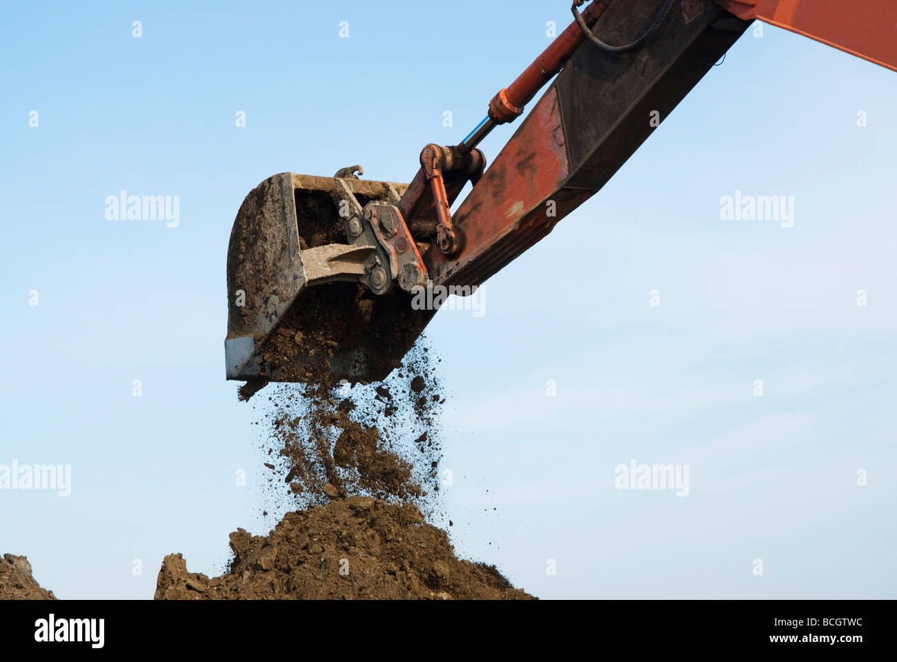 an excavator dumping a bucket of dirt Stock Photo - Alamy