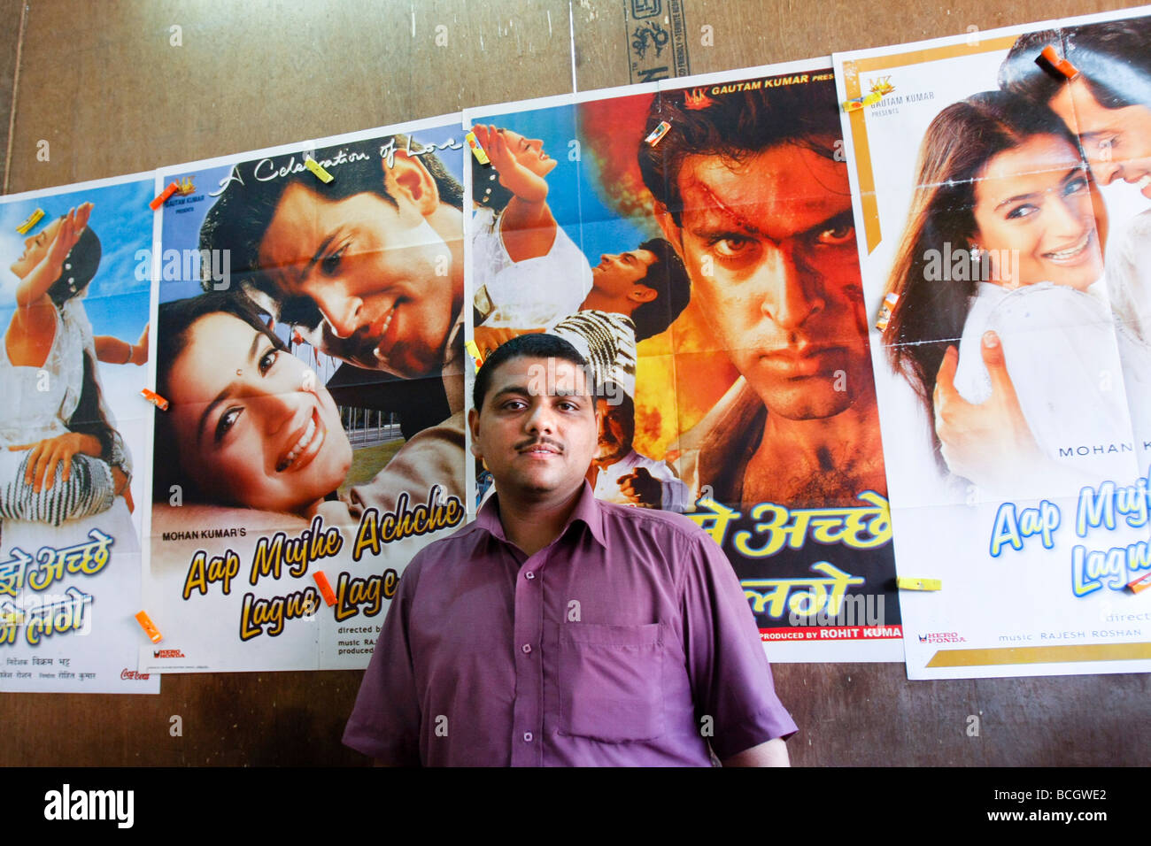 AN owner of a small cinema stands in front of Bollywood film posters in the slum area of Dharavi in Mumbai (Bombay) in India Stock Photo