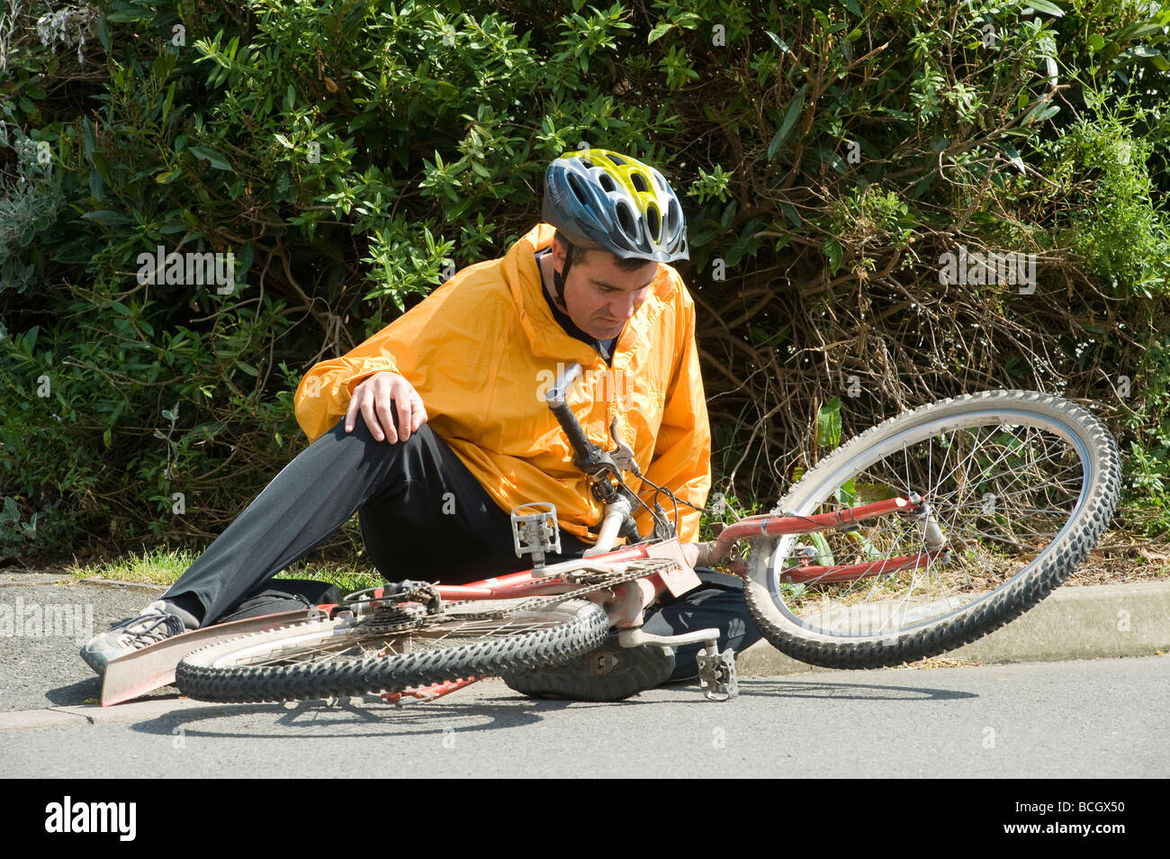Cyclist sitting on the ground following a fall from his bike Stock Photo