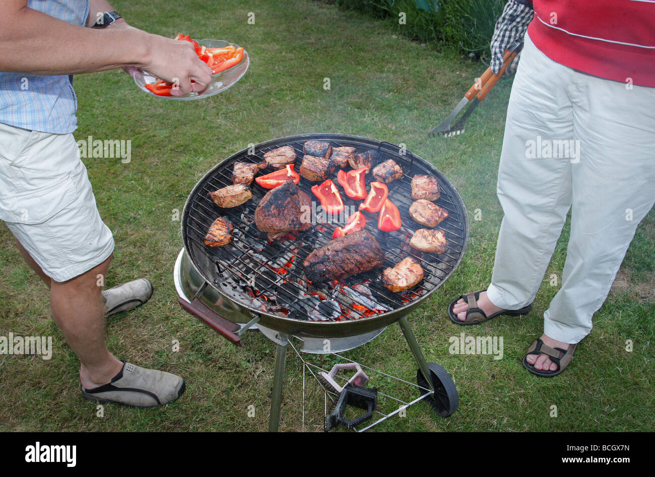 Barbeque Sweden typical Swedish family having a traditional bbq at summer men by the grill cooking the fillet of beef and pork Stock Photo