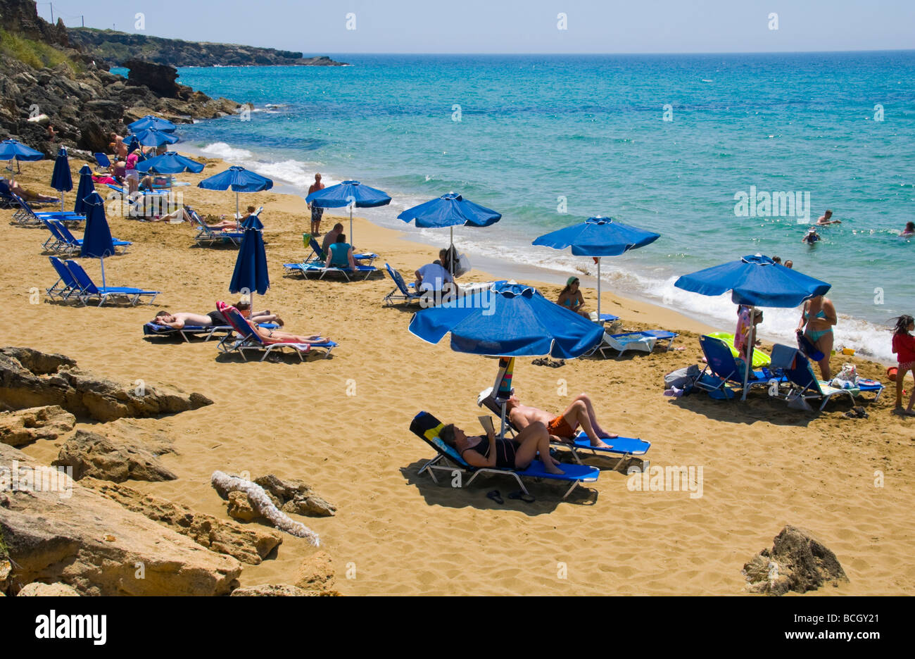 Tourists relaxing on sunbeds under umbrellas on the small sandy Ammes beach on the Greek island of Kefalonia Greece GR Stock Photo