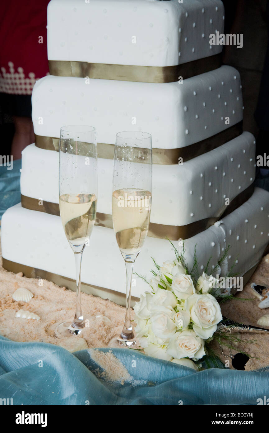 four teired wedding cake with two champagne glasses half full sitting by the cake and wedding bouquet Stock Photo