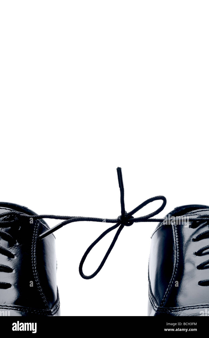 Vertical close up of a pair of black leather business shoes with laces tied together Stock Photo