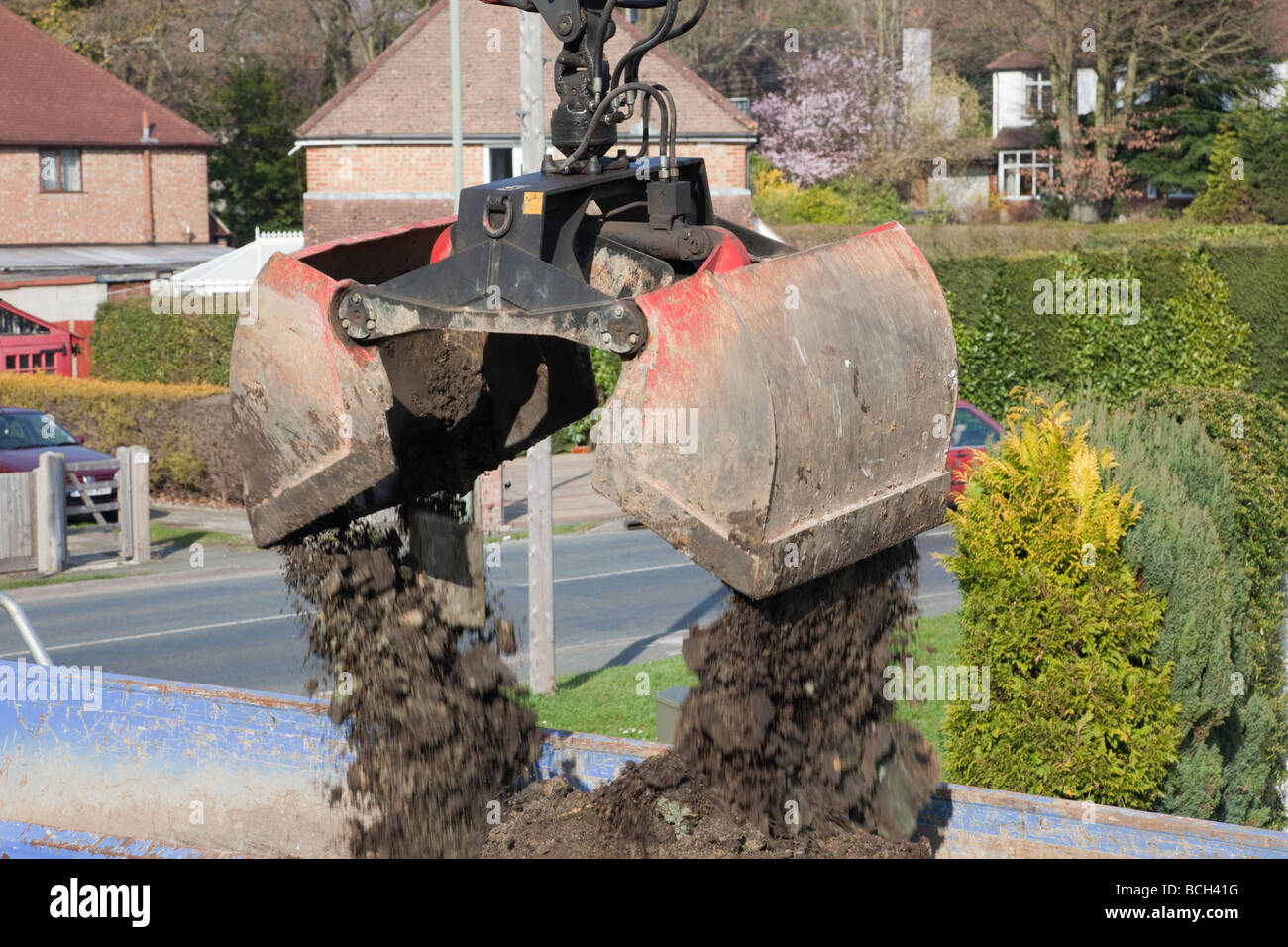 Britain UK Kinshofer Clamshell Bucket KM602 loading grab with horizontal hydraulic cylinder dropping soil into a truck Stock Photo