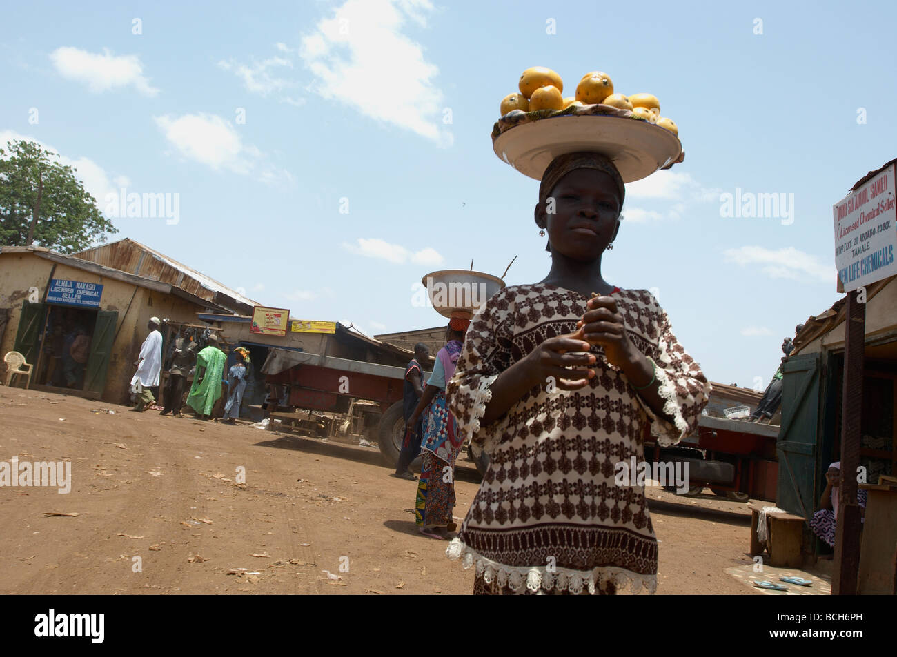 Girl with bowl of oranges on head, market in Tamale Ghana Stock Photo