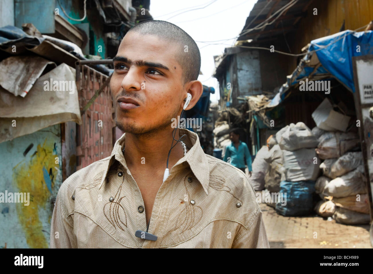 A young man listens to music through earplugs in the poor slum area of Dharavi in Mumbai (Bombay) in India. Stock Photo