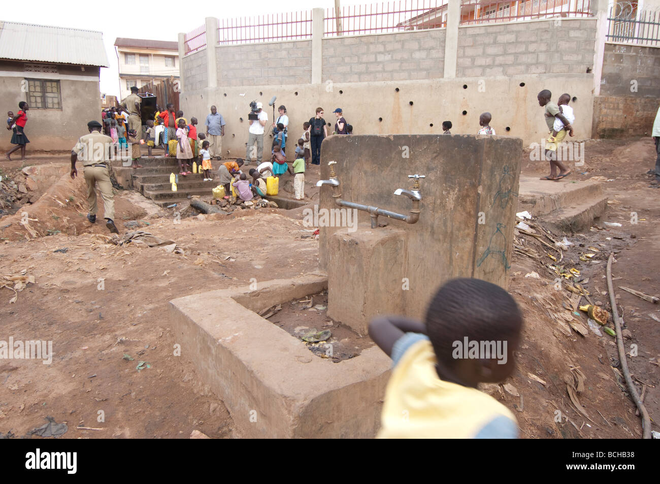 Children playing by private and unused clean water source in African slum Stock Photo