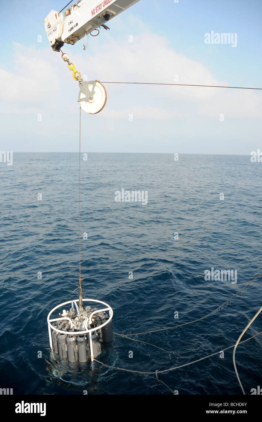Oceanographers lowering a Niskin bottle rosette into the sea Stock Photo