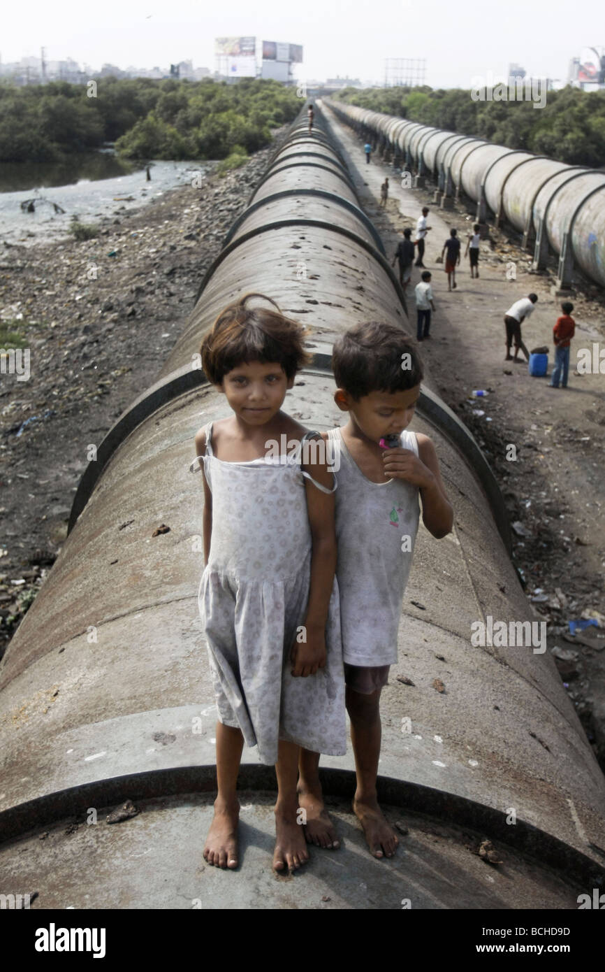 Poor children stand on a water pipe that runs through Dharavi, the largest slum area in Mumbai (Bombay) in India Stock Photo