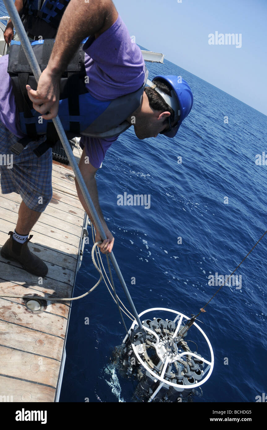 Oceanographers lowering a Niskin bottle rosette into the sea Stock Photo