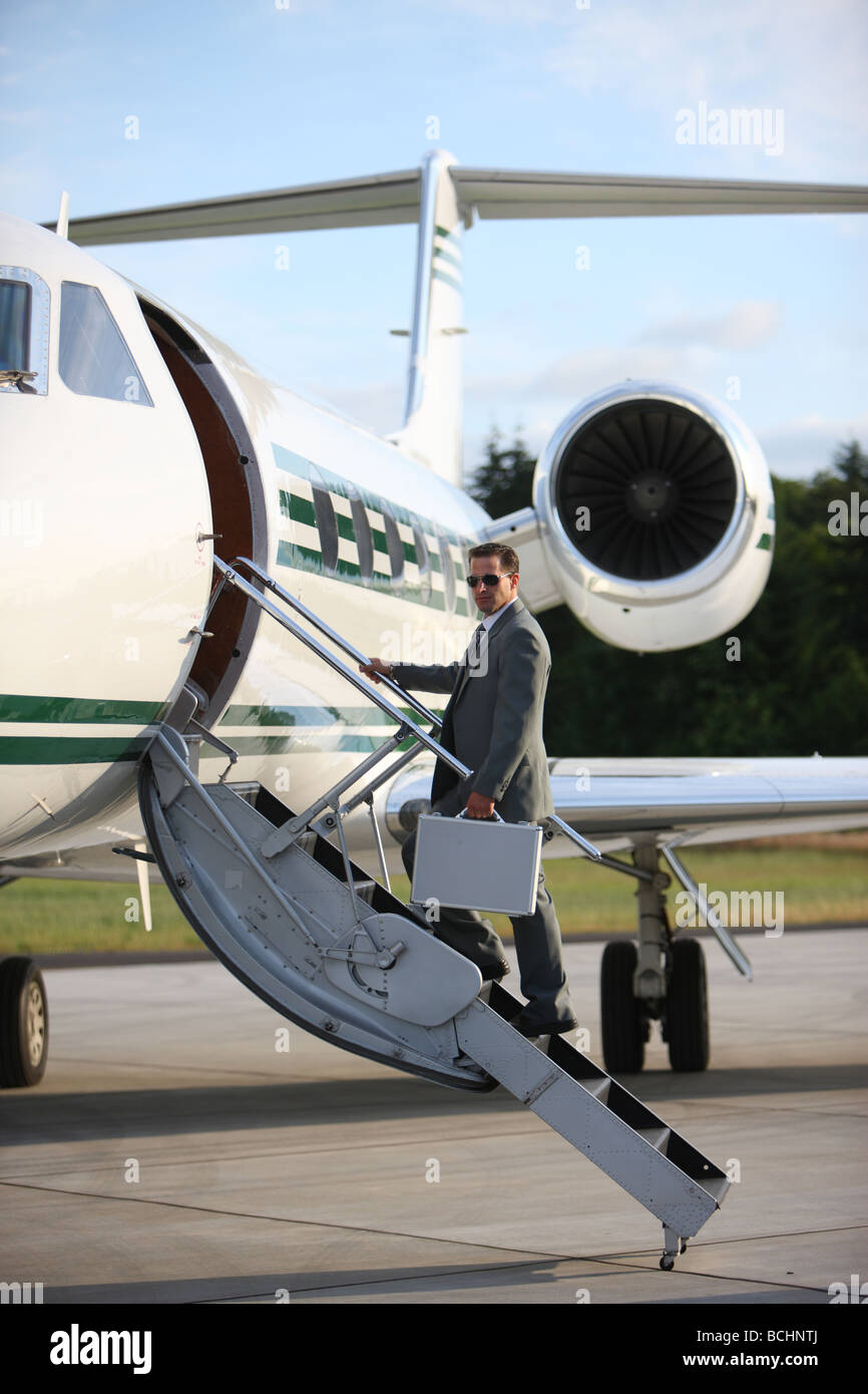 Businessman standing on stairs to private jet Stock Photo
