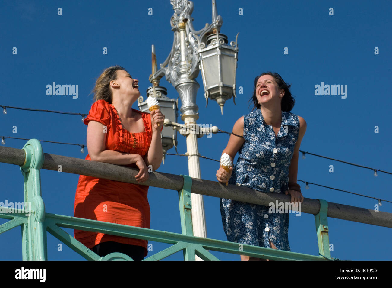 Two girls on the Prom at Brighton with icecream, laughing, having fun. Stock Photo