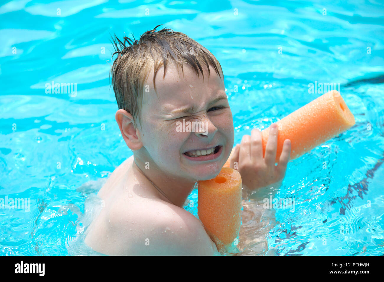 Happy young boy learn how to swim at an outdoor swimming pool Stock