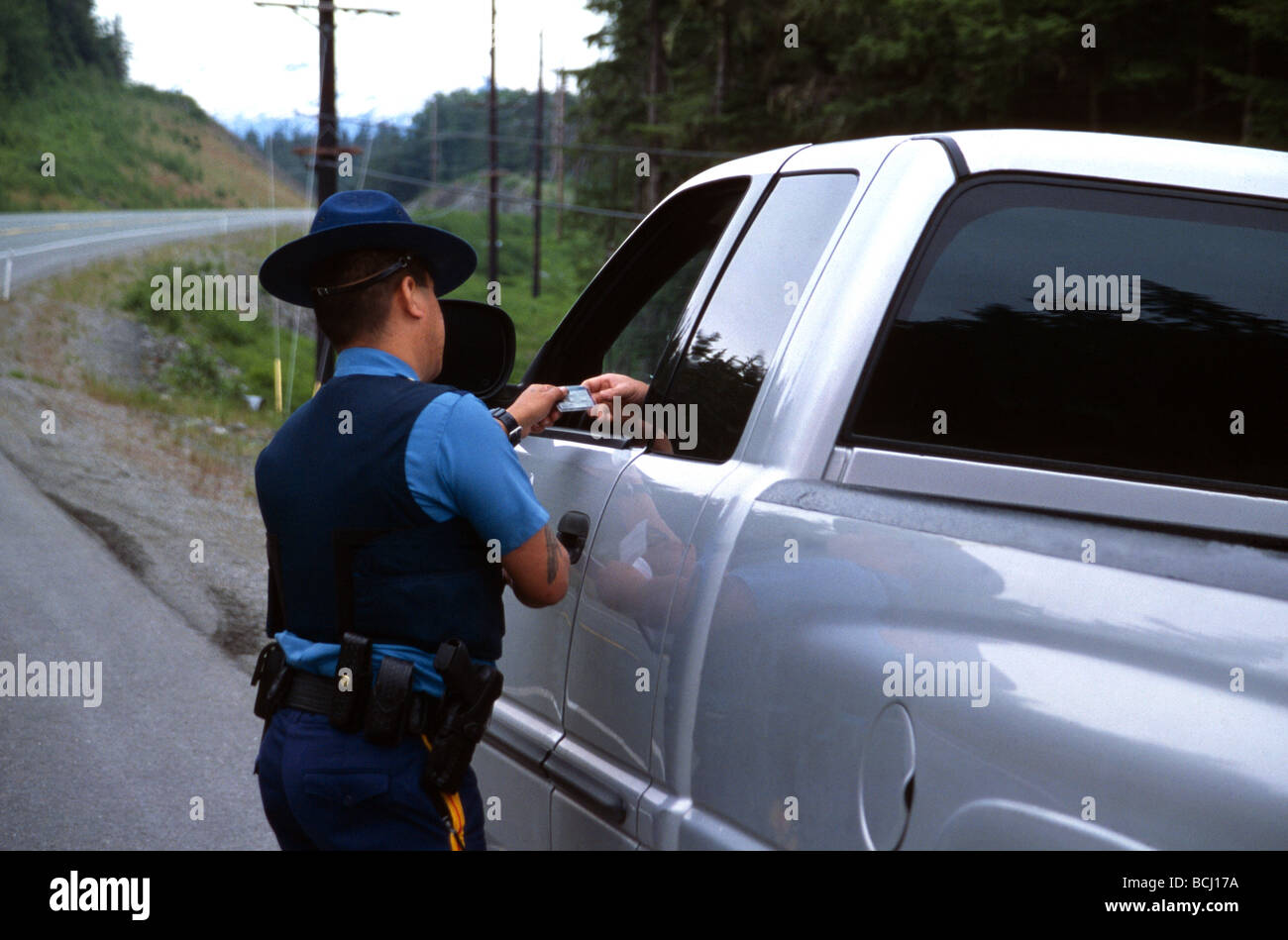 Alaskan State Tropper checking drivers license of a speeding motorist during a traffic stop in Alaska USA Stock Photo