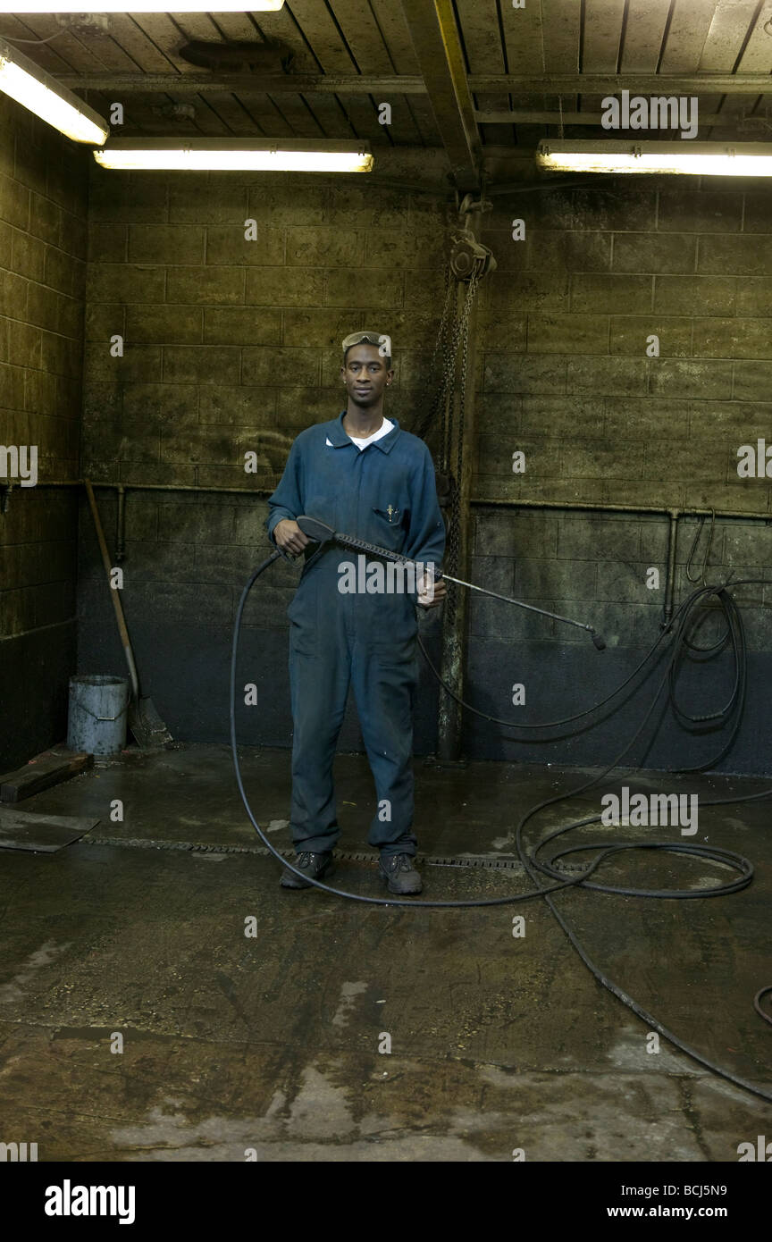 African American male in blue coveralls overalls holding steam cleaning ...