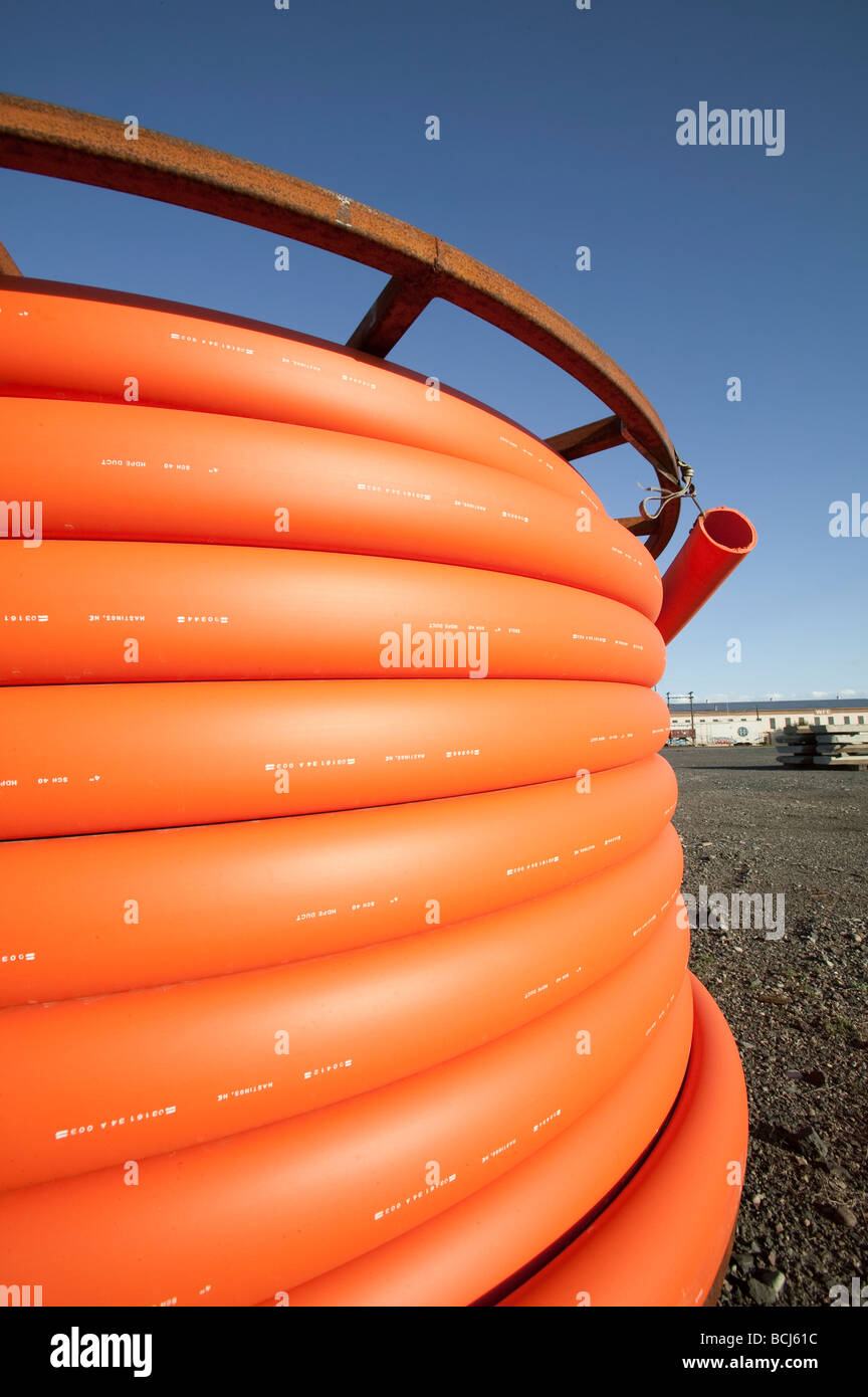 Spool of orange telecommunication cable against sky Stock Photo