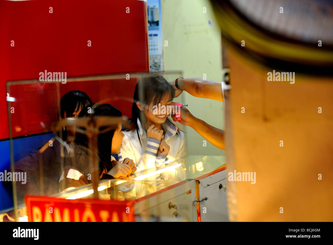 Teenager having her ears pierced in roadside shop. Da Lat, Vietnam Stock Photo