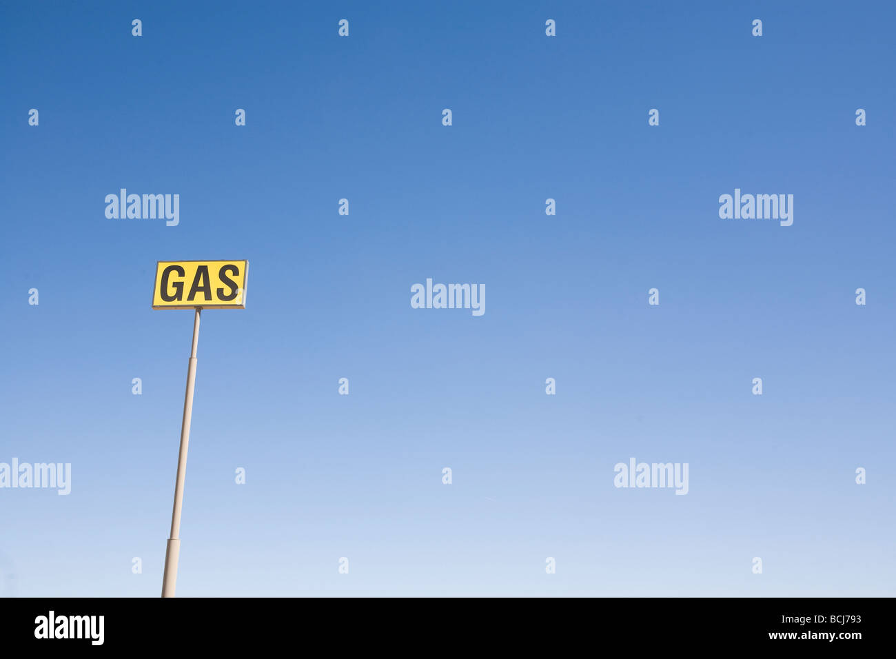 Yellow and black GAS sign on tall pole against blue sky Room for type Stock Photo