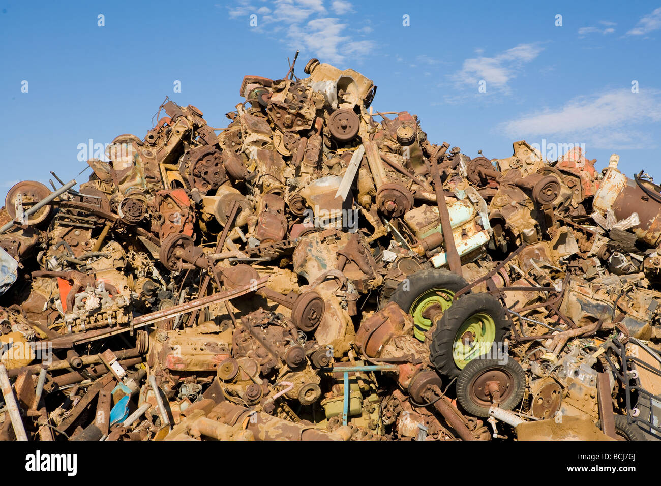 Stack pile of rusted metal car parts including wheels axles tires against sky Barstow California USA Stock Photo