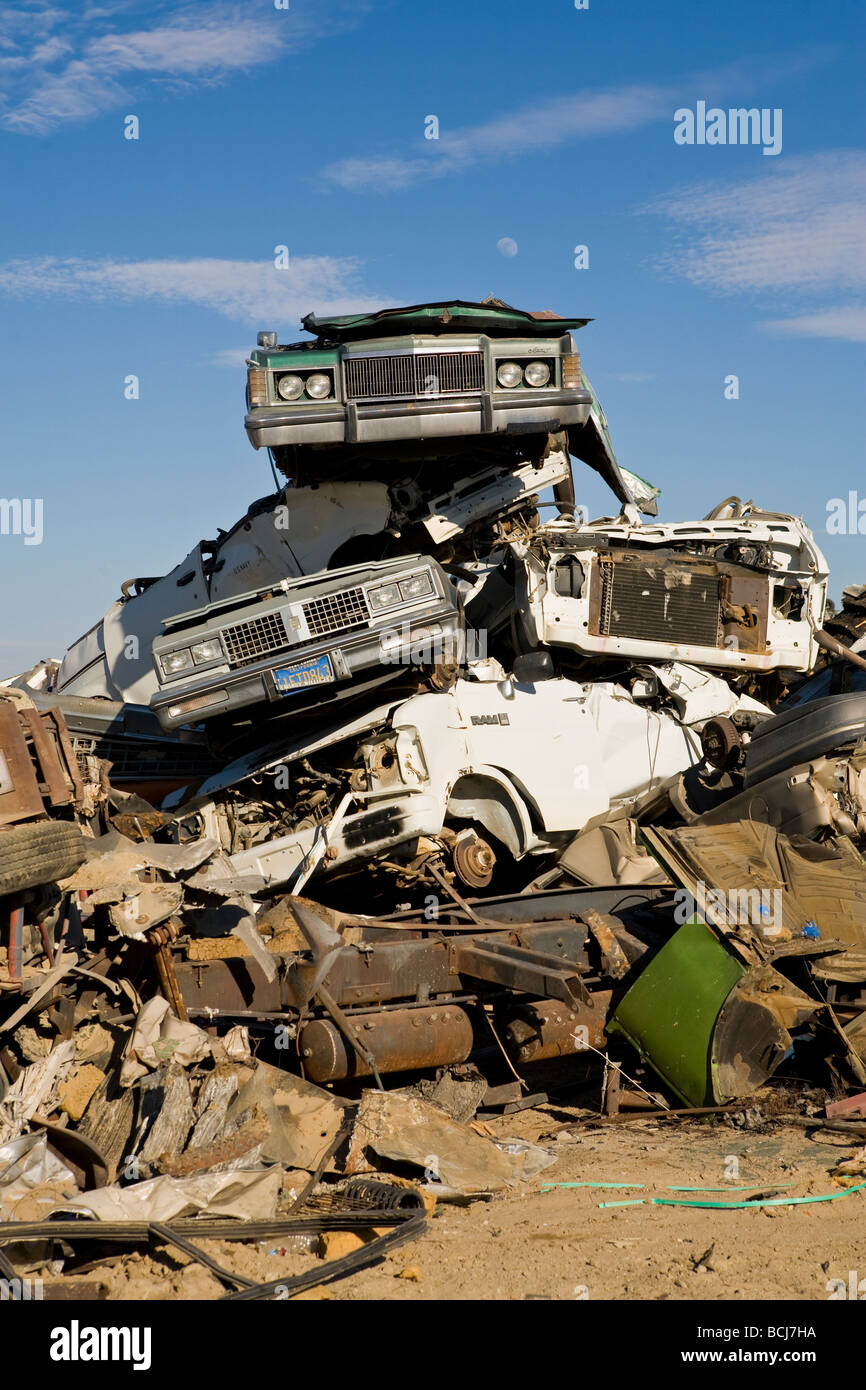 Stack of cars automobiles vehicles in salvage recycling yard against blue sky Barstow California USA Stock Photo