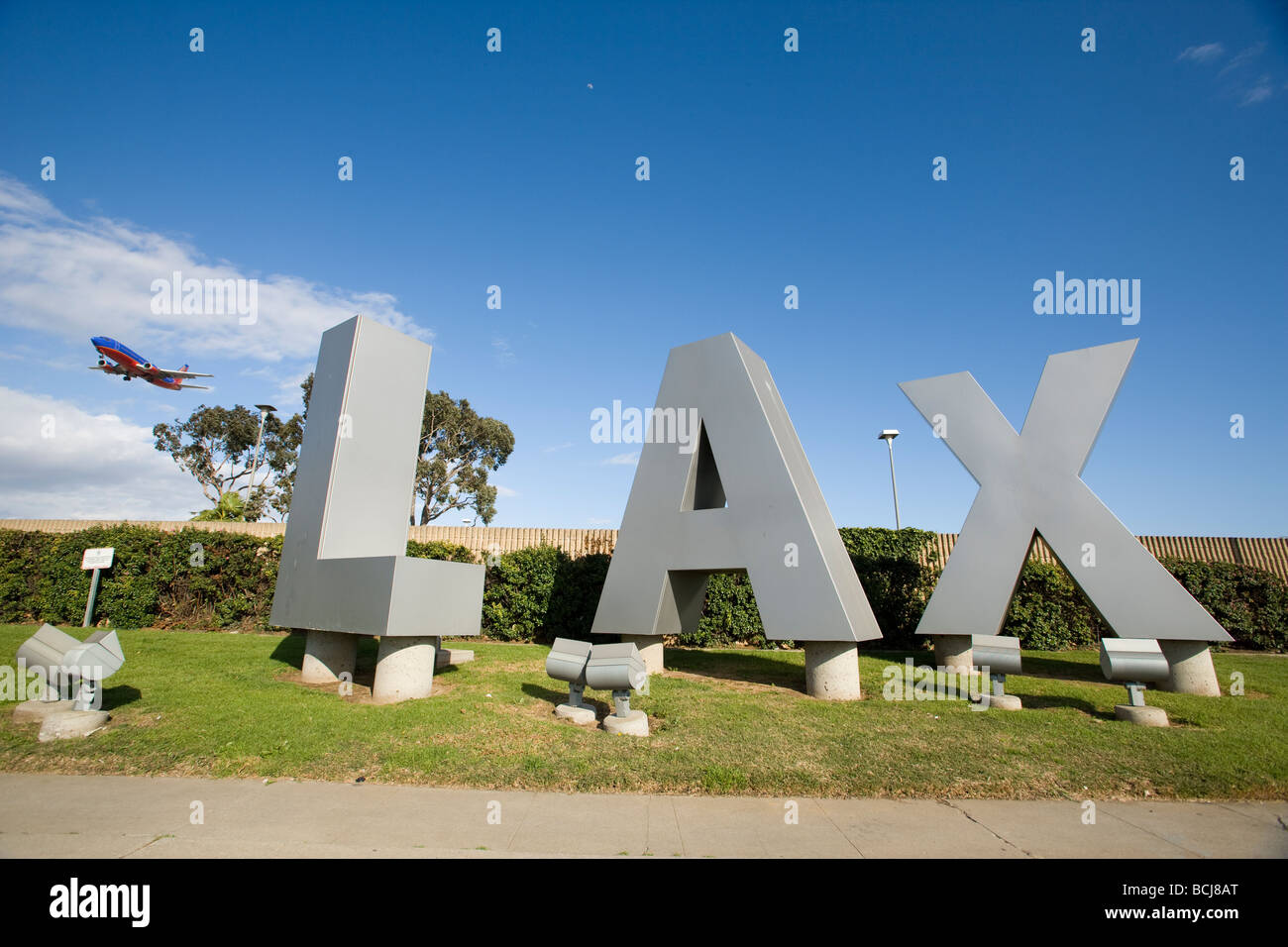 Three dimensional letters spelling out LAX (for Los Angeles International Airport) with jet in sky in background.  California. Stock Photo